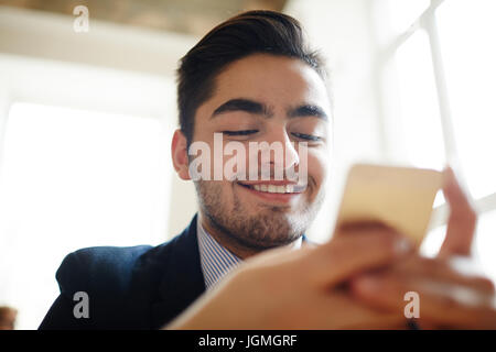 Happy young businessman texting in smartphone Stock Photo