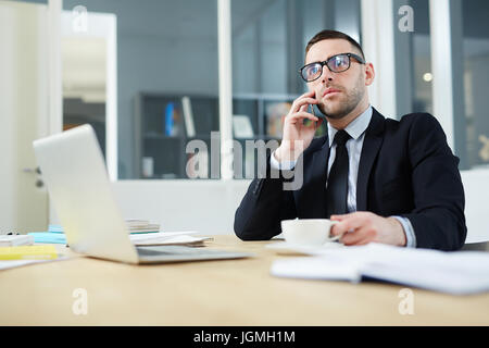 Elegant broker calling on smartphone in office Stock Photo