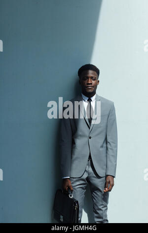 Young business staff leaning against white wall Stock Photo