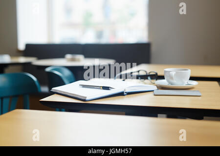 Open notebook, pen, cup of coffee and smartphone on table Stock Photo