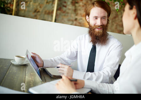Happy agent talking to one of his clients in cafe Stock Photo