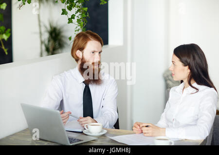 Two young employees having discussion in cafe Stock Photo