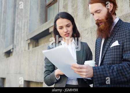 Young economists discussing papers in urban environment Stock Photo