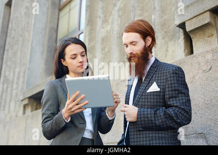 Young economists concentrating on reading online data outdoors Stock Photo