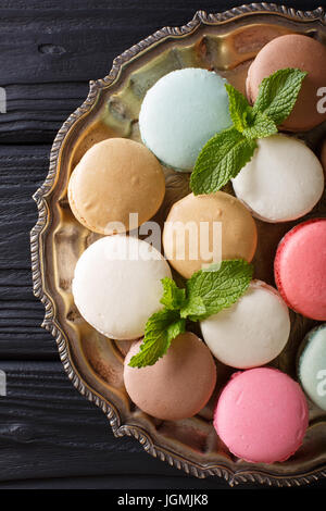 Multicolored macaroons and fresh mint closeup on a platter. Vertical view from above Stock Photo