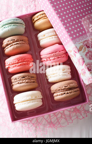 Multicolored macaroons in a gift box close-up on a table. Vertical view from above Stock Photo