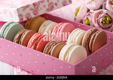 French macaroons in a pink box and flowers close-up on a table. horizontal Stock Photo