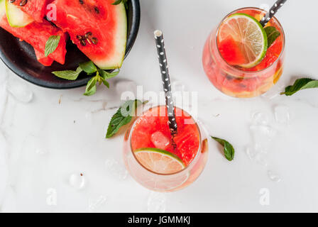 Summer drinks and cocktails. Lemonade, homemade sangria with fresh watermelon, lime, mint and pineapple. In two glasses,  on a white marble table. Cop Stock Photo