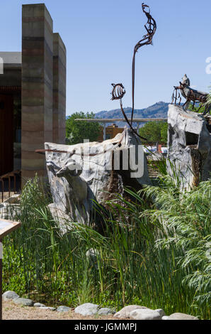 Stone staues of a big horn sheep and howling wolf and metal sculpture of a flying raven near the entrance to the cultural centre. Stock Photo