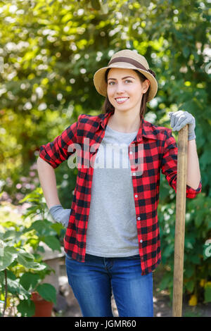 young woman gardener holding spade in garden. People, gardening, planting, hobby concept Stock Photo