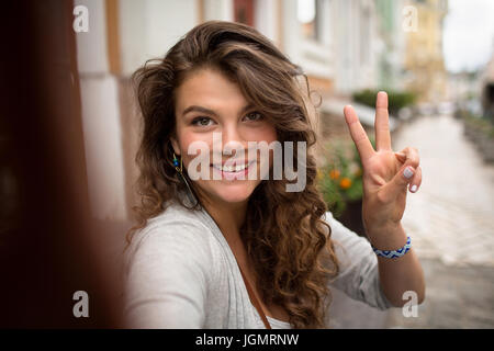 Young travel girl, having fun showing fingers on selfie photo. Stock Photo