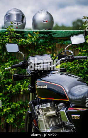 Black motorcycle Kawasaki Z 1300 with two grey motorcycle helmets in the background. Stock Photo