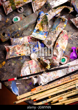 Paint tubes and brushes viewed from above in a creative fine artist's messy studio. Stock Photo