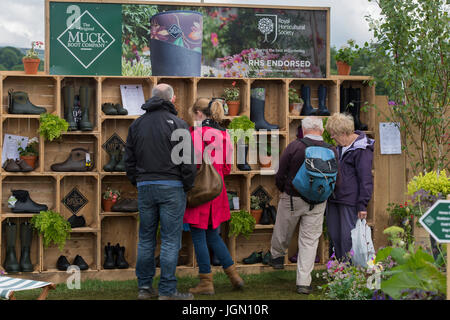 Customers look at boots displayed on Original Muck Boot Company trade stall - RHS Chatsworth Flower Show, Chatsworth House, Derbyshire, England, UK. Stock Photo