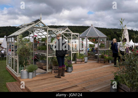 Lady closely inspecting greenhouses on display & for sale at Rhino tradestand - RHS Chatsworth Flower Show, Chatsworth House, Derbyshire, England, UK. Stock Photo