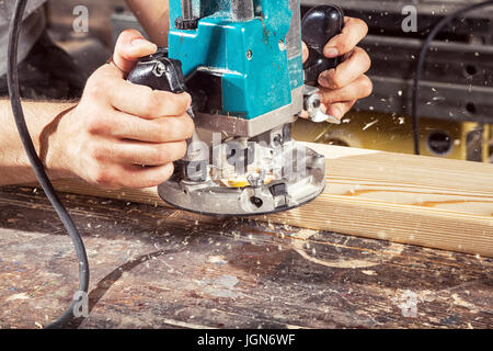 Close-up of how a modern green milling machine works on wood, on a wooden table background Stock Photo