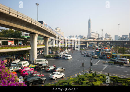 Traffic on approach roads to roundabout at Victory Monument, with pedestrian walkway and BTS Skytrain on viaduct overhead. Bangkok, Thailand Stock Photo
