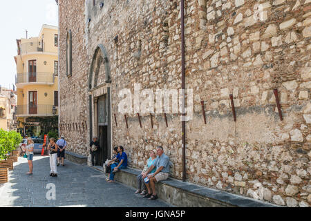 TAORMINA, ITALY - JUNE 29, 2017: visitors near wall of Duomo di Taormina (Cathedral San Nicolo di Bari) in city. Taormina is resort town on Ionian Sea Stock Photo