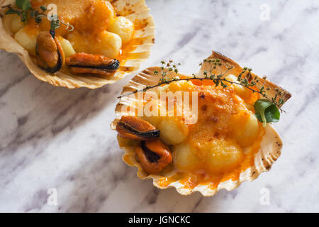 Gnocchi pasta with mussels, tomato and cream room, in vieira shell Stock Photo