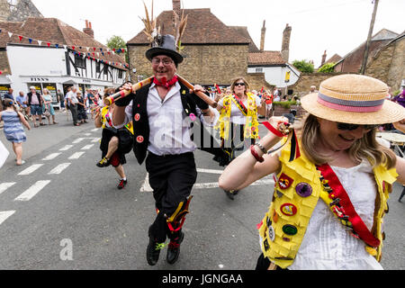 Morris dancers folk dancing in street at the Folk and Ale event, Sandwich. Members of the Kent Korkers and Port Scratchins morris side, dancing directly towards viewer, close up of first dancer, woman. Stock Photo