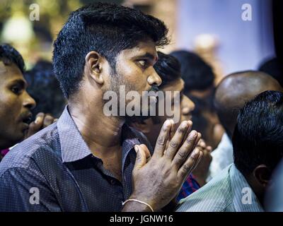 July 9, 2017 - Singapore, Singapore - A Hindu man prays in Sri Veeramakaliamman Temple in Singapore's ''Little India.'' There are hundreds of thousands of guest workers from the Indian sub-continent in Singapore. Most work 5 Â½ to six days per week. On Sundays, the normal day off, they come into Singapore's ''Little India'' neighborhood to eat, drink, send money home, go to doctors and dentists and socialize. Most of the workers live in dormitory style housing far from central Singapore and Sunday is the only day they have away from their job sites. Most work in blue collar fields, like constr Stock Photo