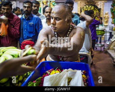 July 9, 2017 - Singapore, Singapore - A Hindu priest hands out bananas that have been blessed in Sri Veeramakaliamman Temple in Singapore's ''Little India.'' There are hundreds of thousands of guest workers from the Indian sub-continent in Singapore. Most work 5 Â½ to six days per week. On Sundays, the normal day off, they come into Singapore's ''Little India'' neighborhood to eat, drink, send money home, go to doctors and dentists and socialize. Most of the workers live in dormitory style housing far from central Singapore and Sunday is the only day they have away from their job sites. Most w Stock Photo