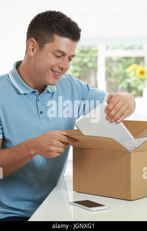 Man At Home Unwrapping Digital Tablet Bought Online Stock Photo