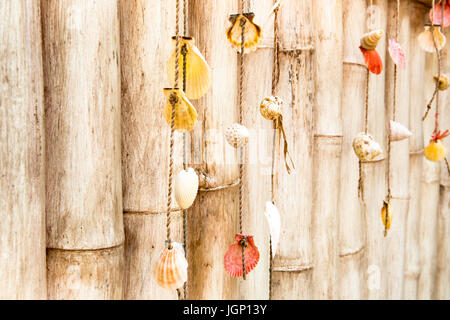 Homemade ornaments from sea shells on a bamboo fence Stock Photo