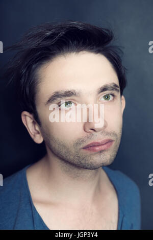Portrait of  young green-eyed man with bristles on his face. Studio photo on  black background Stock Photo