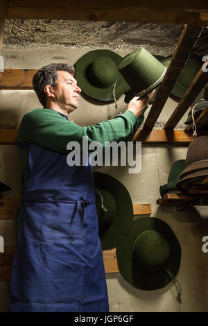 Hatter placing wool felt hat with shaping cord to dry on wooden boards in drying room, hatmaker workshop, Bad Aussee, Styria Stock Photo