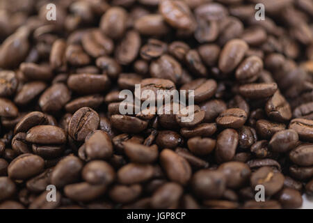 Coffee beans close up and piles on white background. Stock Photo