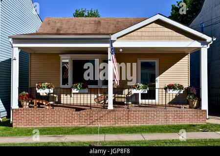 Small house with American flag hanging from front porch Stock Photo