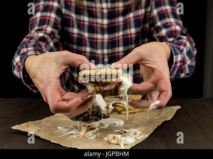 Womans Hands Hold a Gooey Marshmallow Smore with dripping melted marshmallow Stock Photo