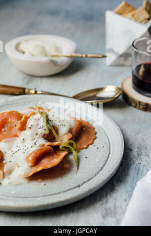 Carrot  pasta stuffed with cheese and vegetables, with béchamel sauce, set table. Stock Photo