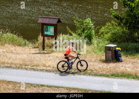 Young woman cycling on a cycle path along the river Berounka, Czech Republic bike Europe
