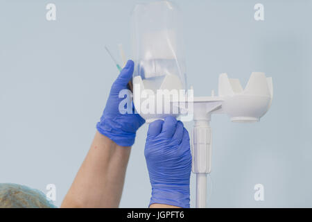 Doctor's hands and infusion drip in hospital on blurred background Stock Photo
