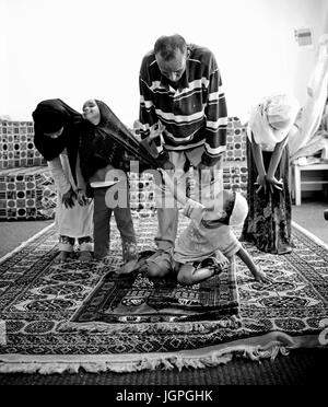 Somali refugee family in their new home in Portland, Oregon - a young boy grabs his sisters hijab during Muslim family prayer. Stock Photo