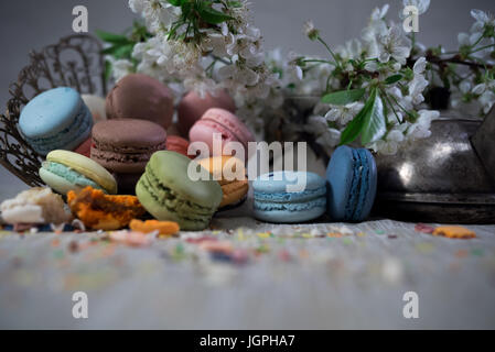 Multicolor macaroons on a table with eastern vase and cherry branch in blossom Stock Photo