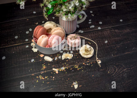 White jug with a branch of cherry blossoms and macaroons in a white deep dish Stock Photo