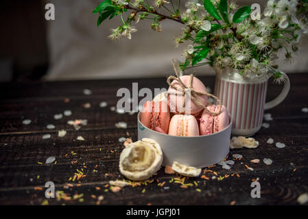 White jug with a branch of cherry blossoms and macaroons in a white deep dish Stock Photo