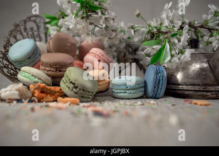 Multicolor macaroons on a table with eastern vase and cherry branch in blossom Stock Photo