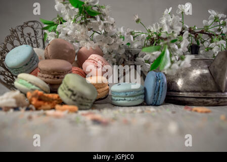 Multicolor macaroons on a table with eastern vase and cherry branch in blossom Stock Photo