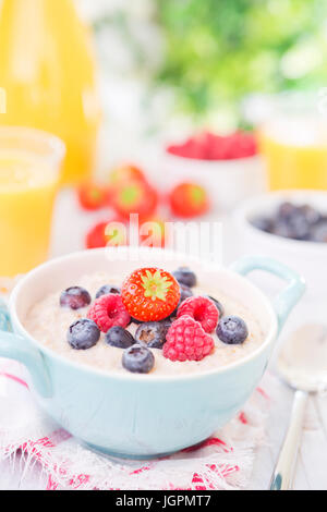 A bowl with homemade oatmeal porridge with fresh fruit on a rustic outdoor table. Stock Photo