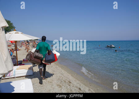 Street vendor selling popular brands replicas bags by a Greek beach shore on sunny summer day. Stock Photo