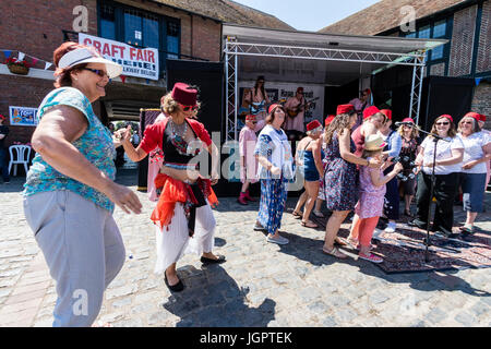 The music group, the Fabulous Fezheads performing a concert at the Folk and Ale event at Sandwich, Kent. Members of the public and band including their belly dancer, dancing in front of the stage in the town square. Stock Photo