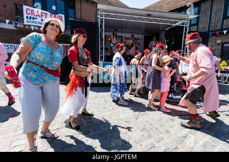 The music group, the Fabulous Fezheads performing a concert at the Folk and Ale event at Sandwich, Kent. Members of the public and band including their belly dancer, dancing in front of the stage in the town square. Stock Photo