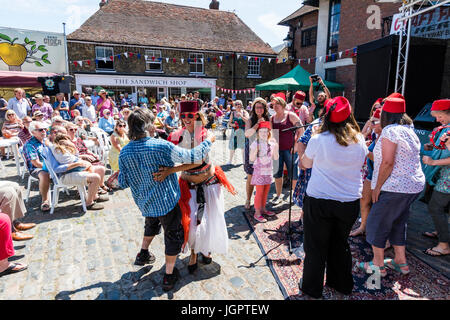 The music group, the Fabulous Fezheads performing a concert at the Folk and Ale event at Sandwich, Kent. Members of the public and band including their belly dancer, dancing in front of the stage in the town square. Stock Photo