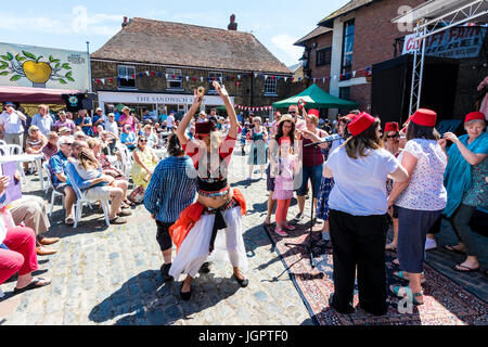 The music group, the Fabulous Fezheads performing a concert at the Folk and Ale event at Sandwich, Kent. Members of the public and band including their belly dancer, dancing in front of the stage in the town square. Stock Photo