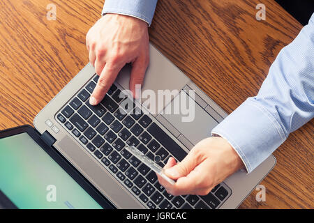 Male hands holding credit card and pressing enter key, top view - online shopping Stock Photo