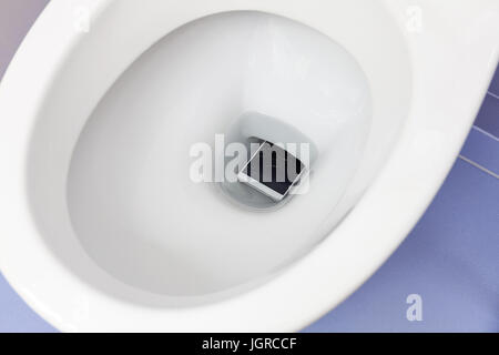 Broken mobile phone dropped into toilet bowl Stock Photo